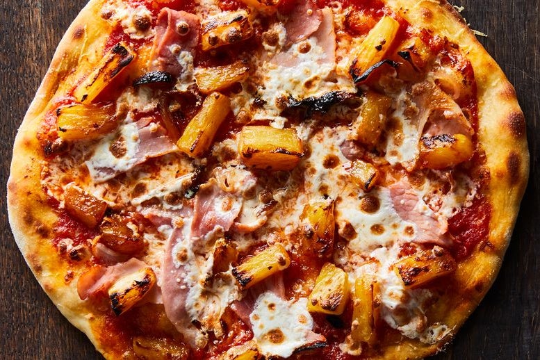 A full pizza with ham, cheese and pineapple on top.